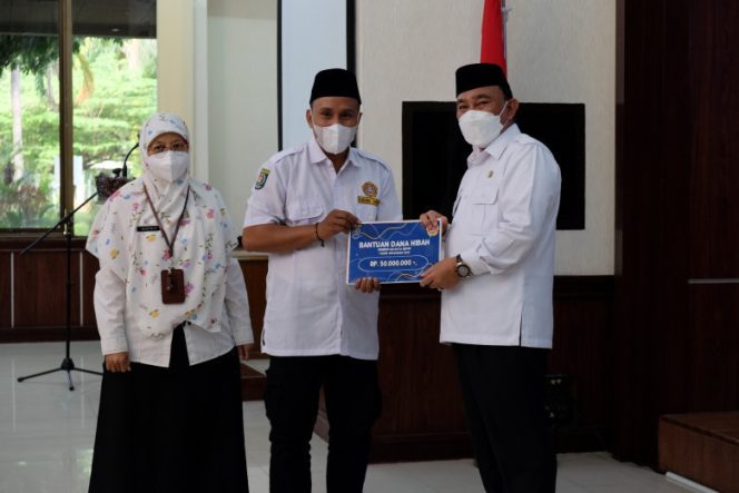 
					Wali Kota Depok, Mohammad Idris didampingi Kepala Dinsos Kota Depok, Asloe'ah Madjri menyerakahkan dana hibah Rp 50 juta kepada Ketua Katar Kelurahan Sukamaju, Idham Kholid, beberapa waktu lalu. (Foto: JD 01/Diskominfo)