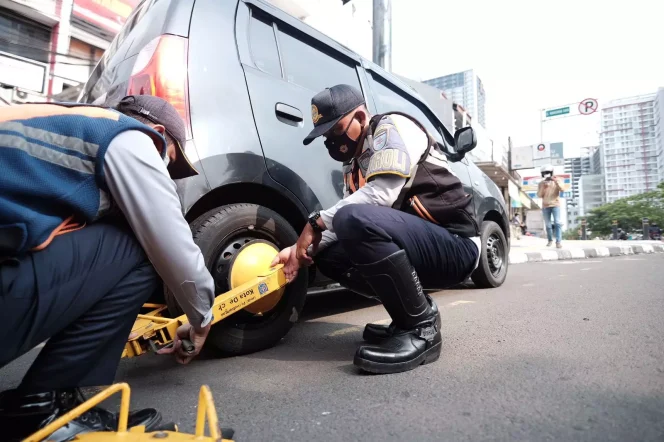 
					Petugas Dishub Kota Depok melakukan penggembokan terhadap mobil yang parkir di badan Jalan Raya Margonda, Selasa (14/03/23). (Foto : JD01/Diskominfo).