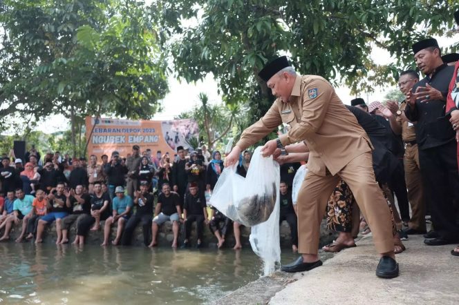 
					Wali Kota Depok, Mohammad Idris menebar ikan kedam kolam sebagai tanda dimulainya acara ngubek empang. (Foto : JD01/Diskominfo)
