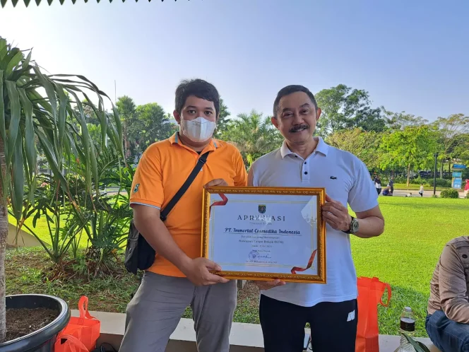 
					HRD Manager PT Immortal Cosmedica Indonesia Julius Heru Suhartono (kanan) menunjukan piagam penghargaan bagi perusahaan yang konsisten menerapkan KTR, di Alun-alun Kota Depok, Sabtu (10/06/23). (Foto: Diskominfo).
